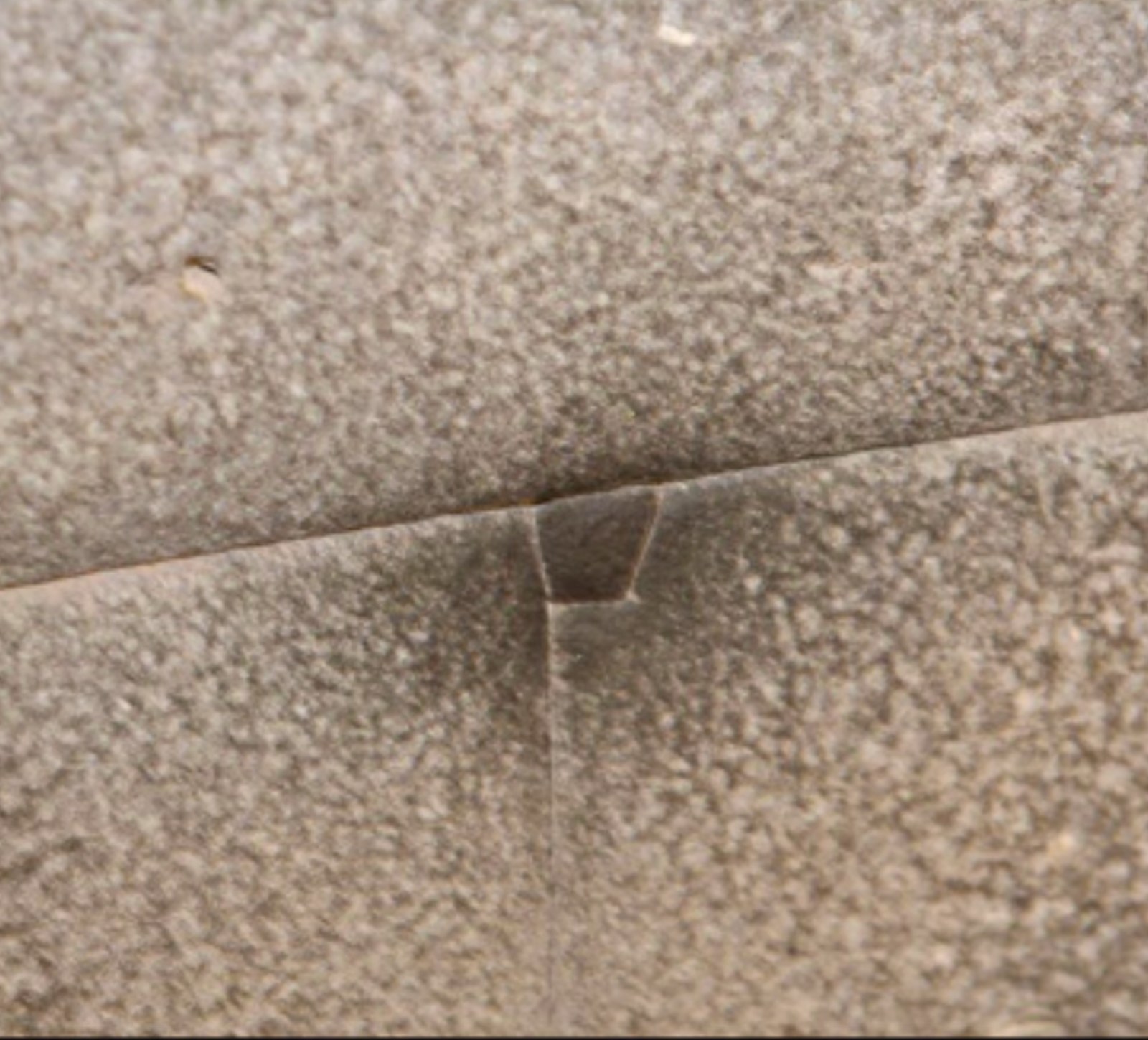 Coricancha mini megalith: a precision-cut keystone-shaped stone bridging the seam between two large polygonal blocks in Cusco.