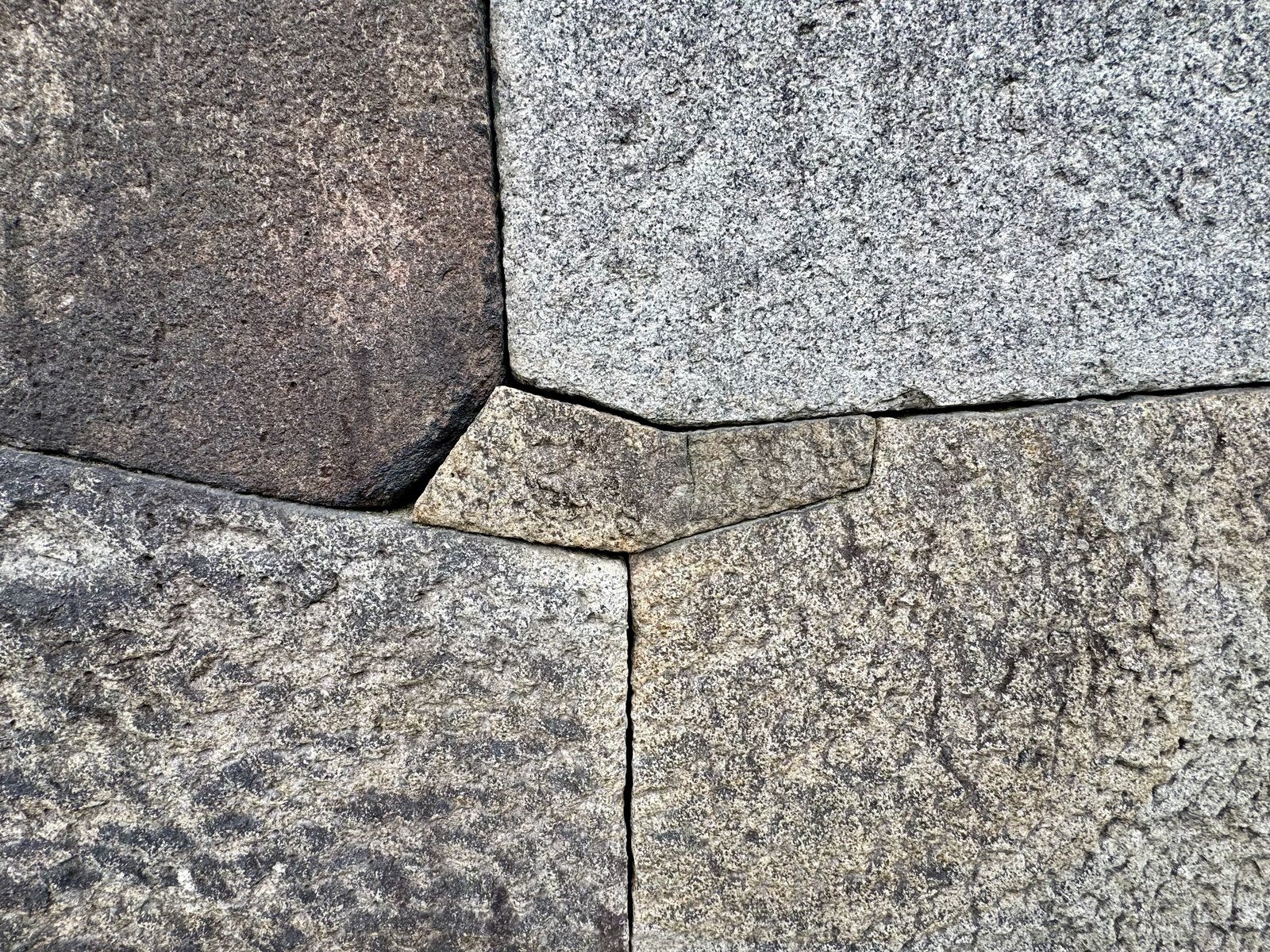 Osaka Castle mini megalith: a precision-cut keystone-shaped insert locking the intersection of four large granite blocks of varying color.
