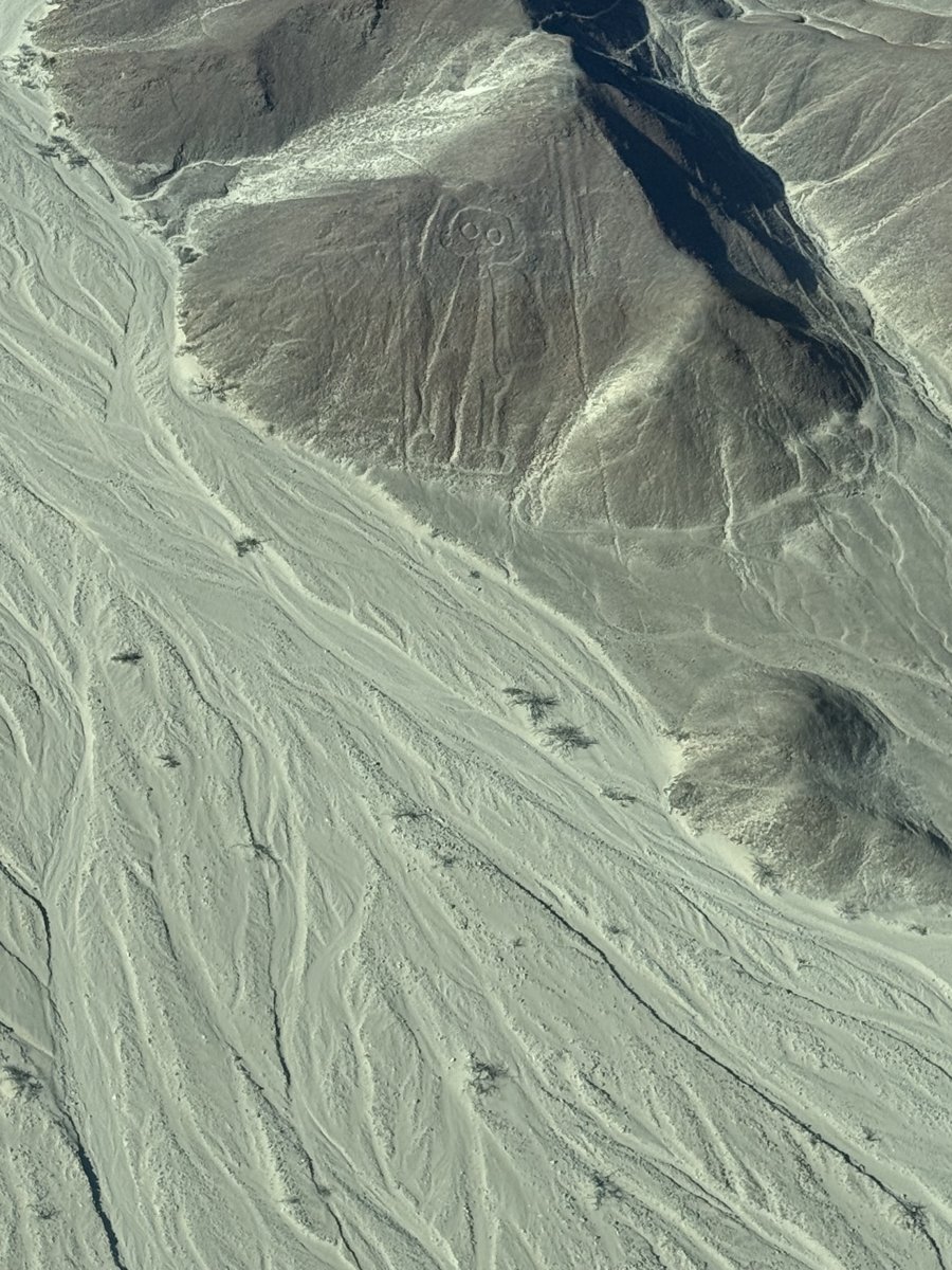 The Owl Man or Astronaut geoglyph on a Nazca hillside, a humanoid figure with a round head and a raised hand.